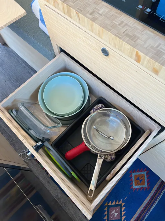 RV rental kitchen setup: a tidy drawer filled with essential cookware, bowls, and glass containers.. Ford Transit 2022