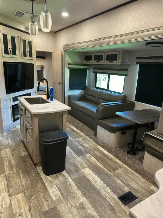 This rv rental boasts a modern, spacious interior with a kitchen island, sofa, dinette, and TV. Ideal for travel.. Forest River Sierra 2022
