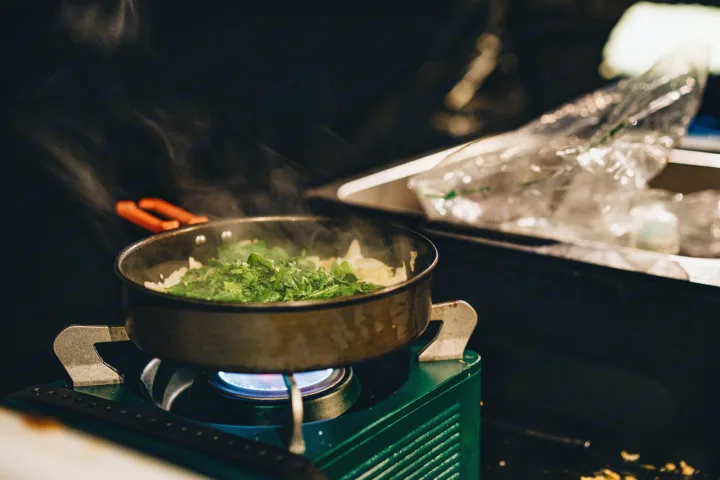 Steam rises from fresh vegetables cooking in a pan on a portable gas stove, ready for an RV rental cooking experience.. Jeep Gladiator 2022