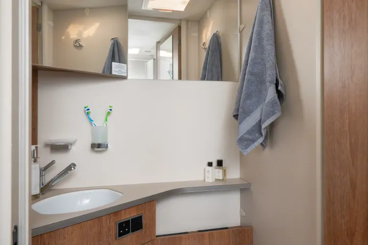 Clean RV rental bathroom with a sink, mirror, toothbrushes, soap, and fresh towel, offering essential amenities.. GlamperRV DBL 2026