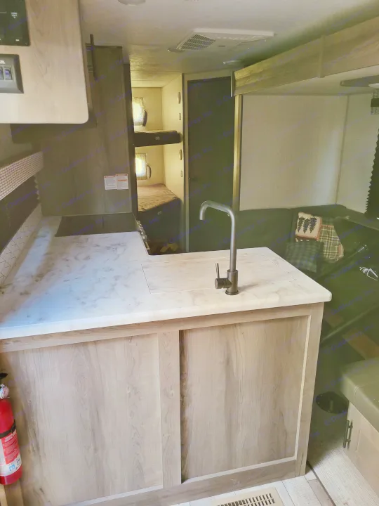 Compact RV rental interior featuring a kitchen with a modern faucet, bunk beds, and cozy living space.. KZ Confluence 2022