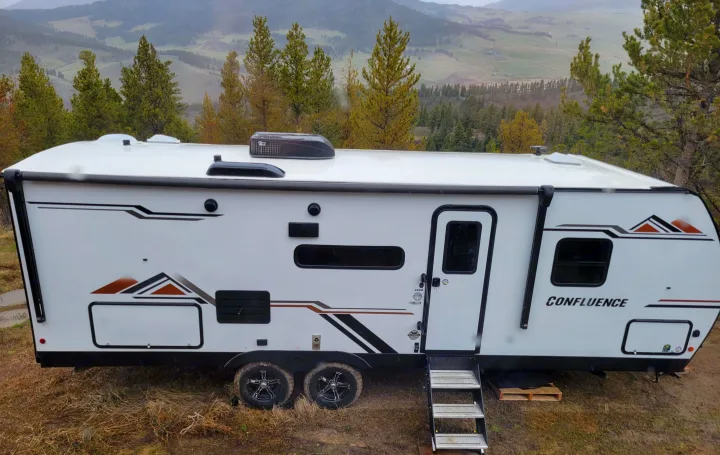 White Confluence RV rental travel trailer parked outdoors with scenic mountain views. Ideal for your next camping trip.. KZ Confluence 2022