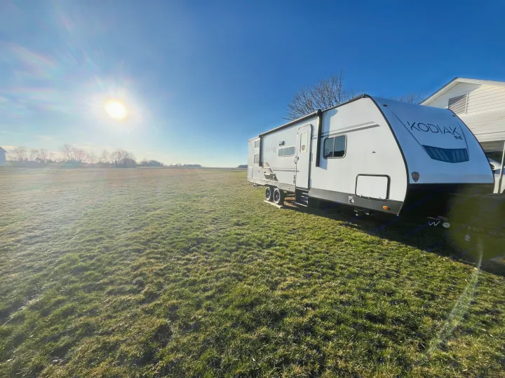 White Kodiak SE RV rental parked on a bright, sunny green field under a clear blue sky, ready for adventure.. Dutchmen Kodiak Bunk House 2019