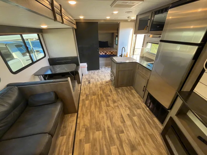 Modern RV rental interior: kitchen, dinette, sofa, & private bedroom. Enjoy comfort on the road!. Dutchmen Kodiak Bunk House 2019