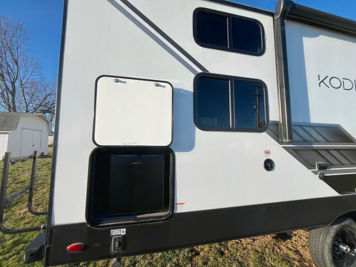 Explore this RV rental's exterior featuring an open compartment with a built-in outdoor refrigerator for convenient camping.. Dutchmen Kodiak Bunk House 2019