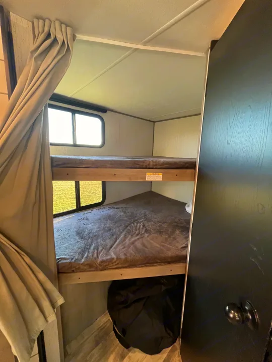 Inside an RV rental: two cozy bunk beds with windows and a privacy curtain, ideal for travelers.. Dutchmen Kodiak Bunk House 2019
