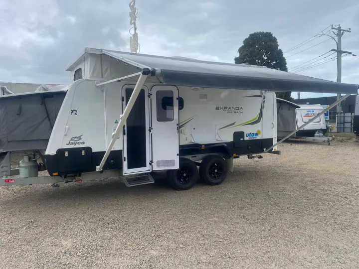 A white Jayco Expanda Outback caravan with an extended awning is parked on a gravel lot, ideal for RV rental adventures.. Jayco 17.56-2.OB.MY18 2018
