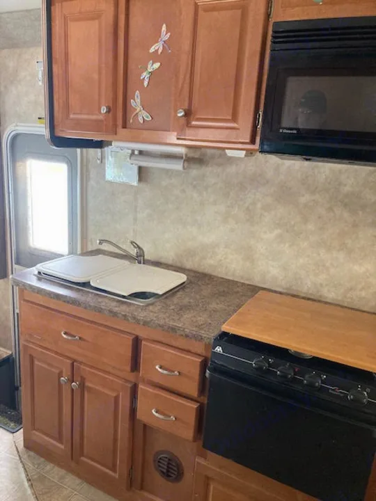 RV rental kitchen: double sink, stovetop/oven, microwave, and wood cabinetry visible. Prepare meals on the road.. Yellowstone Conquest M6254 2008