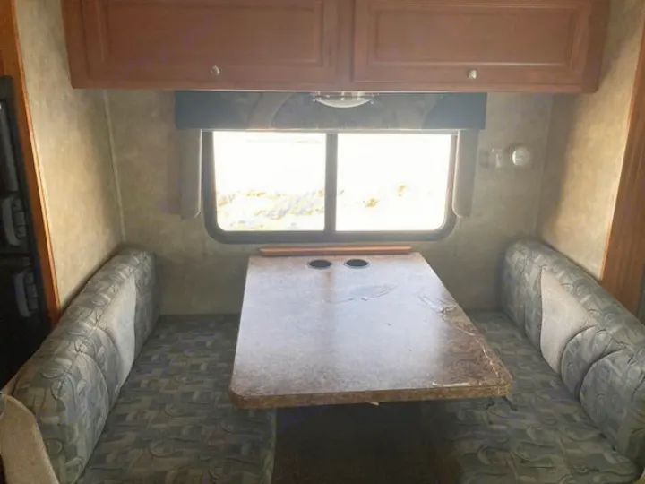 RV rental interior: Dinette area with two opposing benches, a table, a window, and overhead cabinets.. Yellowstone Conquest M6254 2008