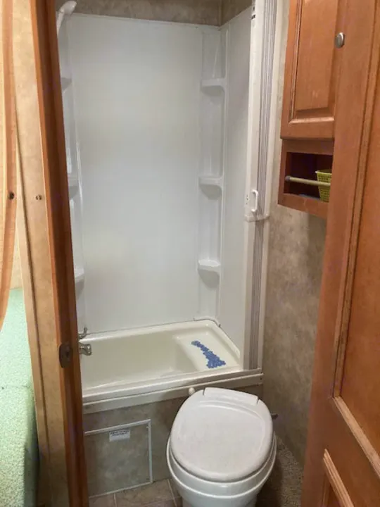 Compact RV rental bathroom features a shower-tub combo and toilet, ideal for travel comfort.. Yellowstone Conquest M6254 2008