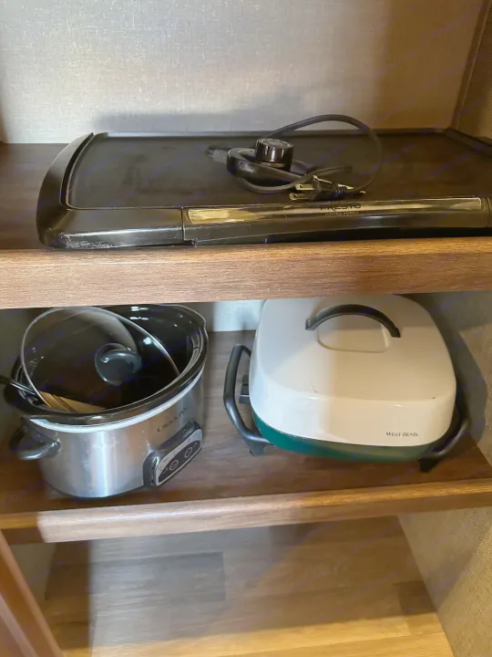 RV rental kitchen appliances: Presto griddle, Crock-Pot, and a West Bend cooker stored in cabinets.. Keystone RV Cougar 2019