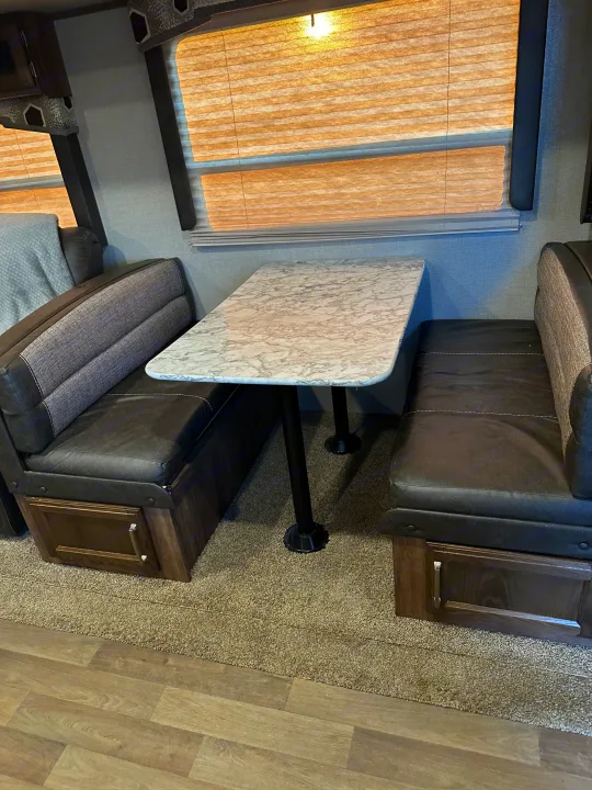RV rental: inviting dinette with marble-look table, dark cushioned benches, and light-filtering blinds.. Keystone RV Cougar 2019