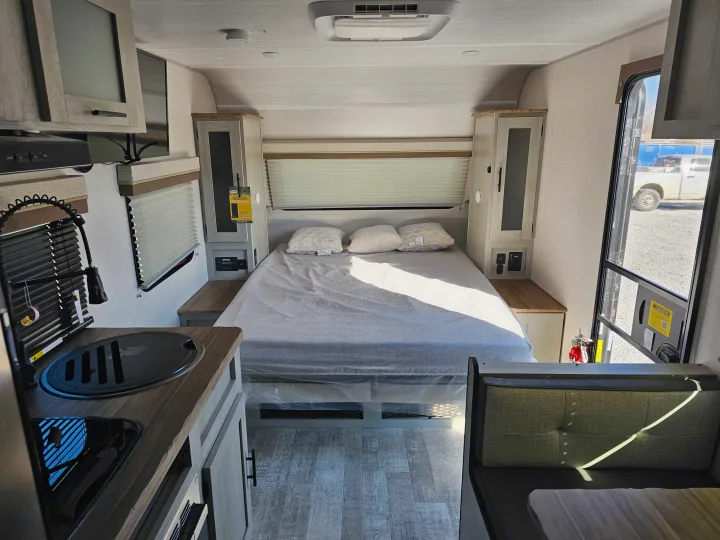 Cozy RV rental interior showcasing a bright bedroom, functional kitchen, and inviting dinette area.. Forest River Ibex 19MBH 2024