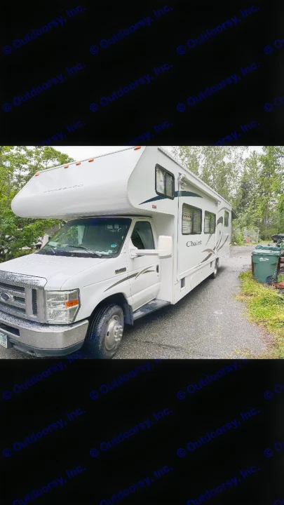 White Winnebago Chalet RV rental, perfect motorhome parked on a wet driveway surrounded by trees.. Winnebago Chalet 2010