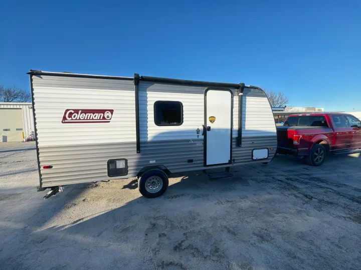 Coleman travel trailer RV rental hitched to a red pickup. Clear sky, ready for your next adventure!. Coleman LT17B 2024
