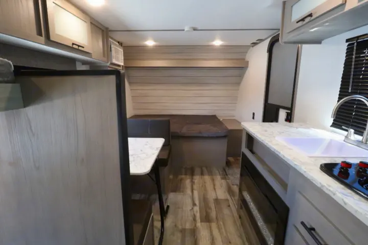 RV rental interior: Features light wood cabinets, kitchen with sink & stove, dinette, and bed area. Ready for travel!. Coleman LT17B 2024