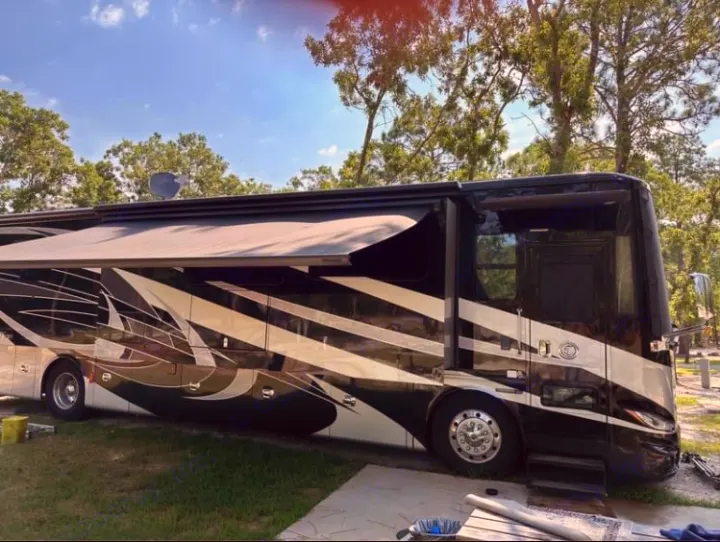 Luxurious black and white RV rental with extended awning at a sunny campsite. Ready for your next adventure.. Tiffin Motorhomes Phaeton 2019