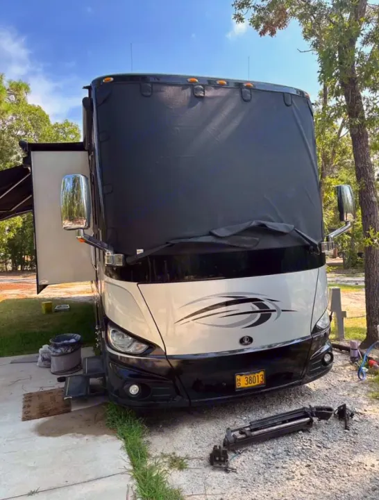 RV rental parked at a campsite, with a large black sunshade on the windshield and steps extended.. Tiffin Motorhomes Phaeton 2019