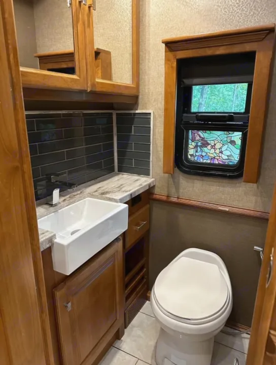 Compact RV rental bathroom with modern sink, tile backsplash, and window. Perfect for your road trip comfort.. Tiffin Motorhomes Phaeton 2019