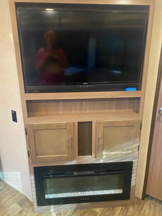 Modern RV rental entertainment setup: TV, storage cabinets, and electric fireplace for cozy nights.. Crossroads RV Sunset Trail 2022
