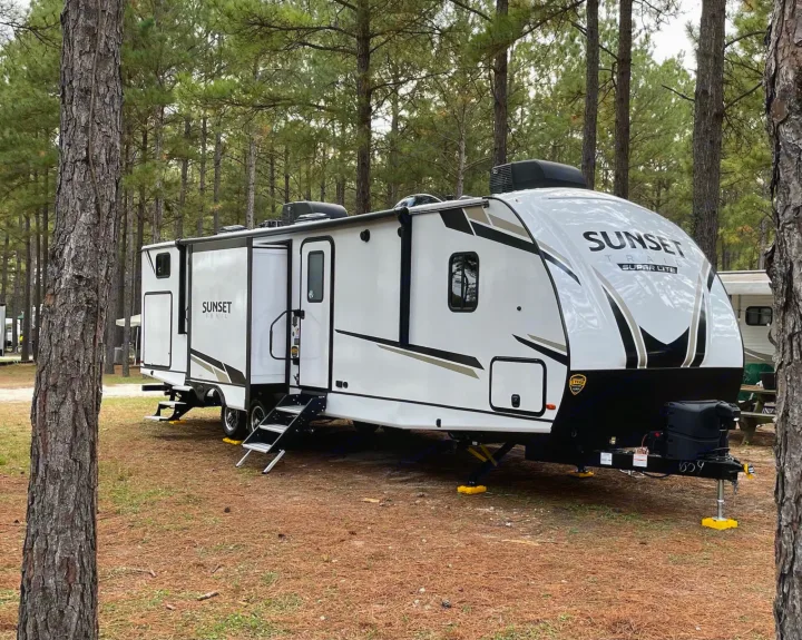 White Sunset Trail RV rental parked in a pine forest campsite, ready for adventure.. Crossroads RV Sunset Trail 2022
