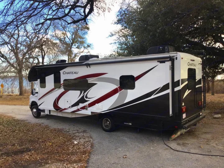 Chateau RV rental parked by a lake at a scenic campground. Explore the outdoors in this comfortable motorhome.. Thor Chateau 2021