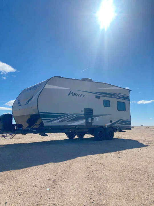 Vortex RV rental under a bright sun, parked on a vast, unpaved landscape. Ideal for travel and outdoor adventures.. Genesis Supreme Rv Genesis Supreme 2022
