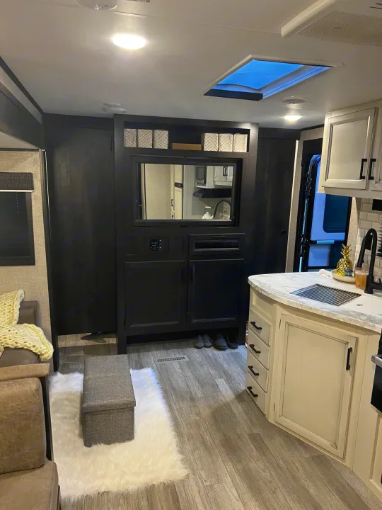 Modern RV rental interior: kitchen with white counters, dark entertainment center, cozy living area.. Jayco Jay Flight 2022