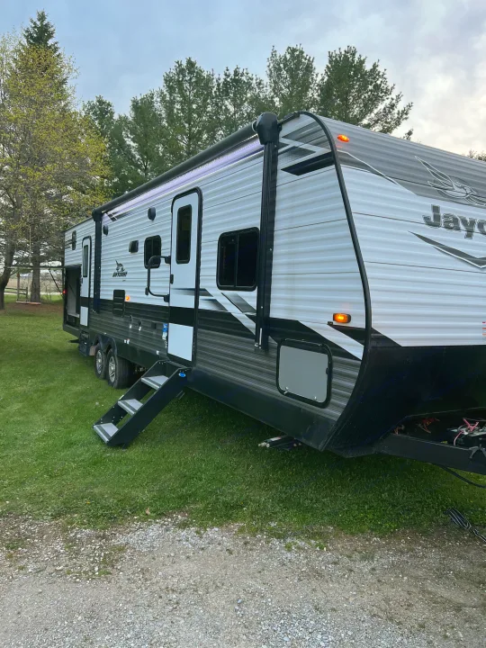 A spacious Jayco travel trailer rv rental is parked on a grassy site with steps down, ready for outdoor adventure.. Jayco Jay Flight 2022