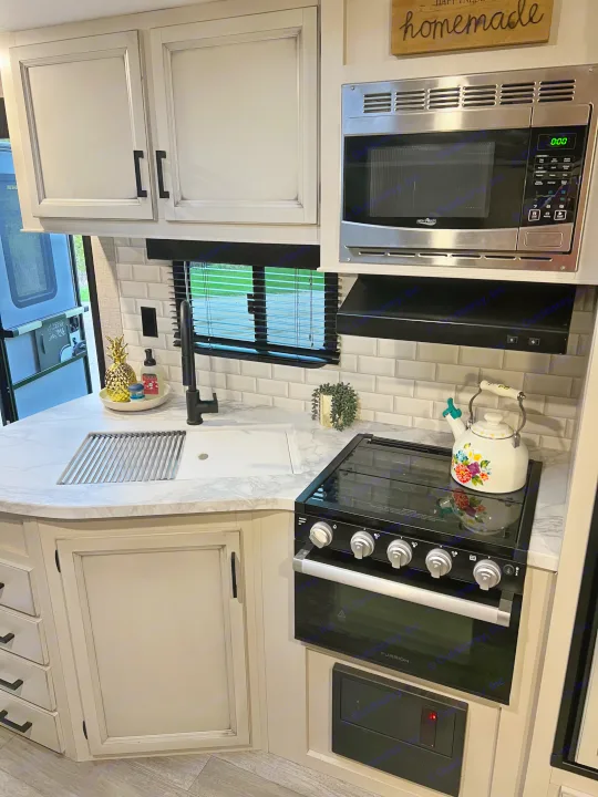 An RV rental kitchen showcasing modern appliances: a High Pointe microwave, Furrion stove, and a functional sink area with subway tile backsplash.. Jayco Jay Flight 2022