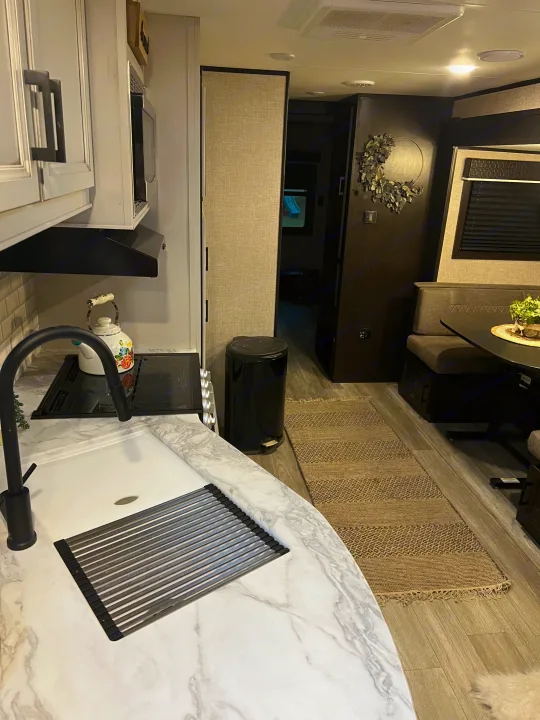 Modern RV rental interior showing a kitchen with marble-look counters, sink, & a comfortable dining booth.. Jayco Jay Flight 2022