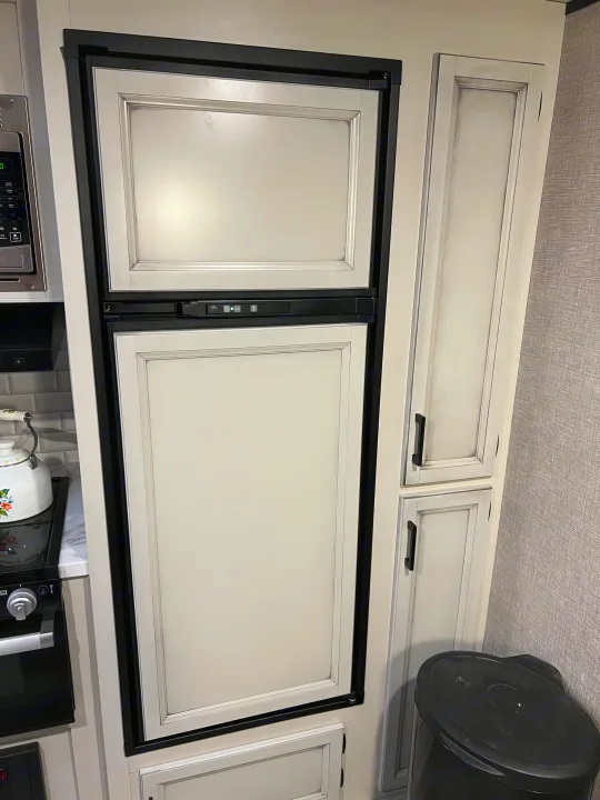 Inside an RV rental: a modern kitchen featuring a panel-ready refrigerator, matching cabinets, microwave, and kettle.. Jayco Jay Flight 2022