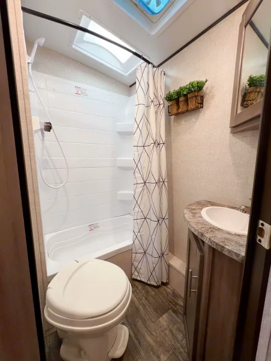 Inside an RV rental: a clean, compact bathroom with shower/tub, toilet, and vanity sink. Modern design.. Crossroads RV Sunset Trail Super Lite 2022