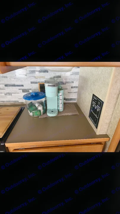 An RV rental's compact kitchen counter featuring a mint Keurig, tea storage, and stylish stacked stone backsplash.. Winnebago Chalet 2010