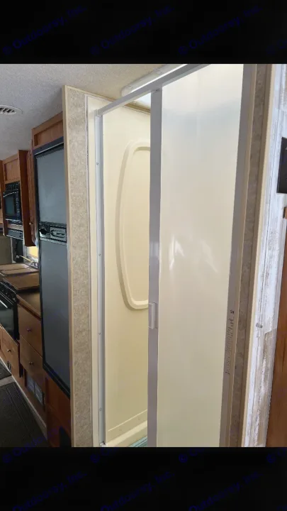 RV rental interior: Compact kitchen with fridge and microwave, adjacent to a bright shower stall.. Winnebago Chalet 2010