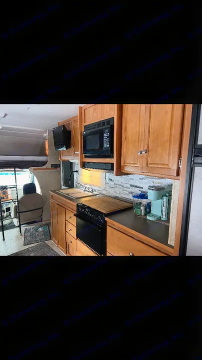 RV rental interior: full kitchen with stove, microwave, sink & a cozy overhead bunk bed. Ready for your adventure.. Winnebago Chalet 2010