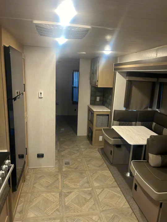 Modern rv rental interior featuring a kitchen, dinette, and living space. Bright lighting and clear pathways are visible.. Forest River 32BHDSX 2023