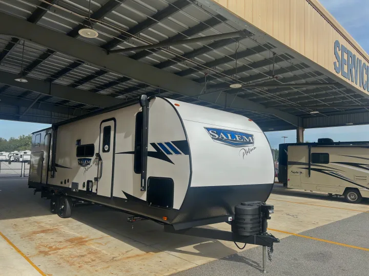 White Salem Platinum travel trailer at an **RV rental** service bay. A motorhome and other RVs are visible.. Forest River 32BHDSX 2023