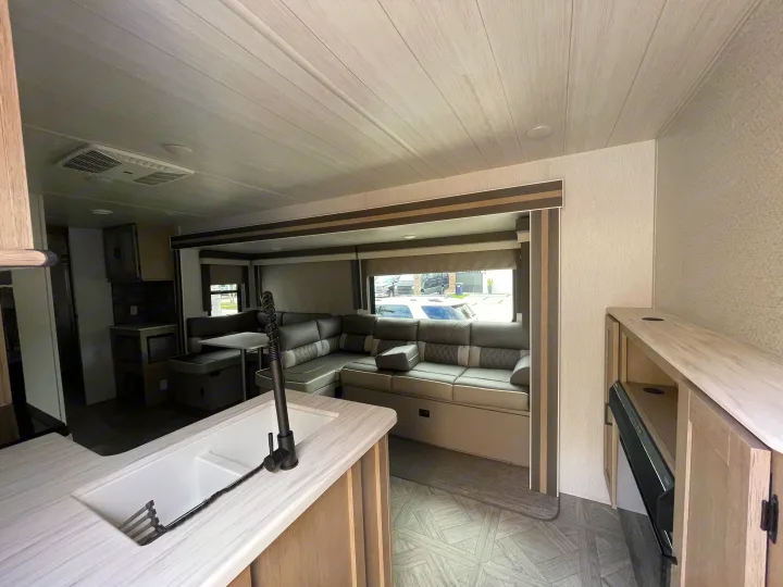 Inside a comfortable RV rental: modern living area with dinette seating, kitchen island, and sleek design.. Forest River 32BHDSX 2023