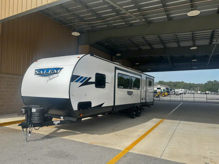 White Salem Platinum travel trailer, a potential rv rental, parked under a shelter. Other RVs are visible in the distance.. Forest River 32BHDSX 2023