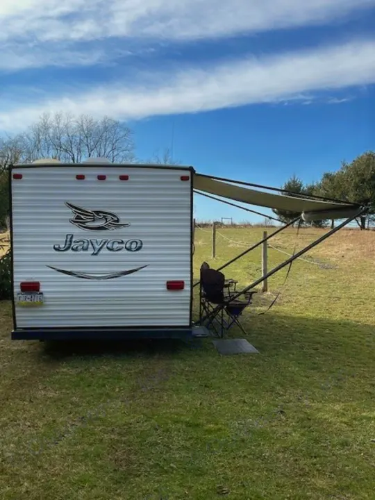 RV rental: Jayco travel trailer in a grassy field, with its awning extended and outdoor seating for relaxation.. Jayco Jay Flight SLX 2015