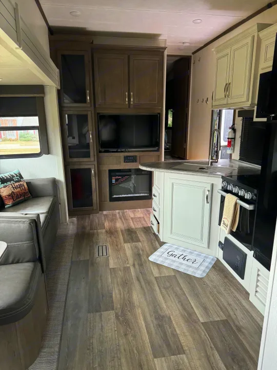 Explore this clean, modern RV rental interior, featuring a full kitchen, comfy dinette, and entertainment center.. Keystone RV Cougar 2023