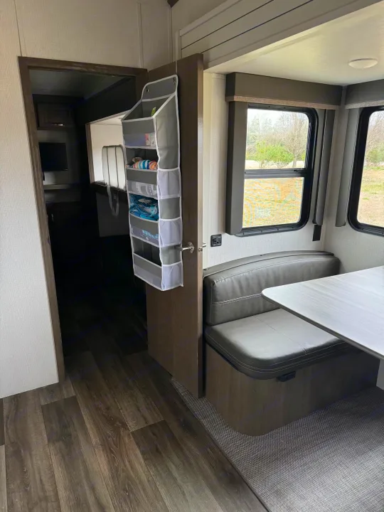 Cozy RV rental interior featuring a dinette, large windows, and practical hanging door storage.. Keystone RV Cougar 2023