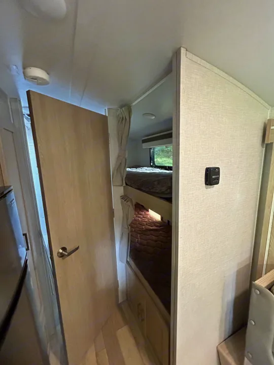 RV rental's functional interior: bunk beds, thermostat, and a glimpse of the compact fridge. Ready for your adventure.. Geo pro Geo pro by rockwood 2022