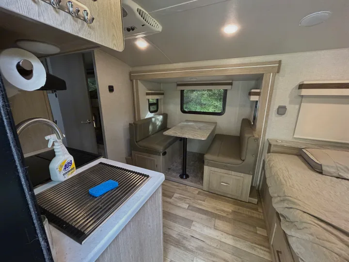 RV rental interior: cozy kitchen, dining booth, and bed area in a modern travel trailer with wood-look flooring.. Geo pro Geo pro by rockwood 2022