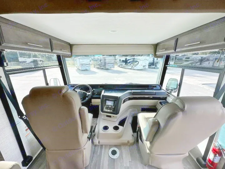 Step inside this spacious RV rental! View of the front cockpit with comfy seats, dashboard, and a large windshield showing other RVs.. Entegra Coach Vision XL 2025