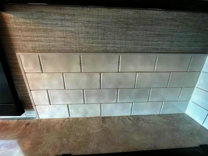 Modern RV rental design: light gray countertop, white subway tile backsplash, and textured gray wall covering create a sleek space.. Entegra Coach Vision XL 2025