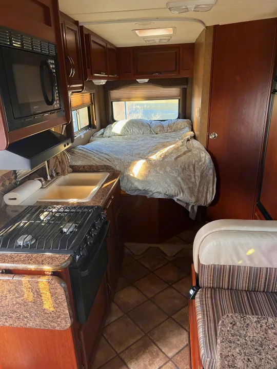 This RV rental offers a compact kitchen, cozy bedroom, and dining space, perfect for travel.. Thor Freedom Elite 2014