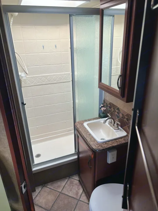 Inside an RV rental: a compact bathroom featuring a shower, sink, and toilet. Designed efficiently for on-the-go comfort.. Thor Freedom Elite 2014