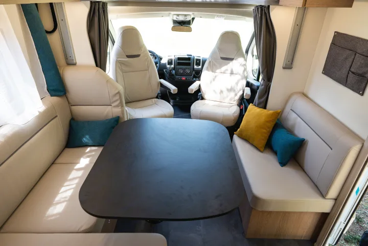 Spacious RV rental interior featuring a dining table, cozy seating, and front cabin views for comfortable road trips.. JOA 75Q 2024